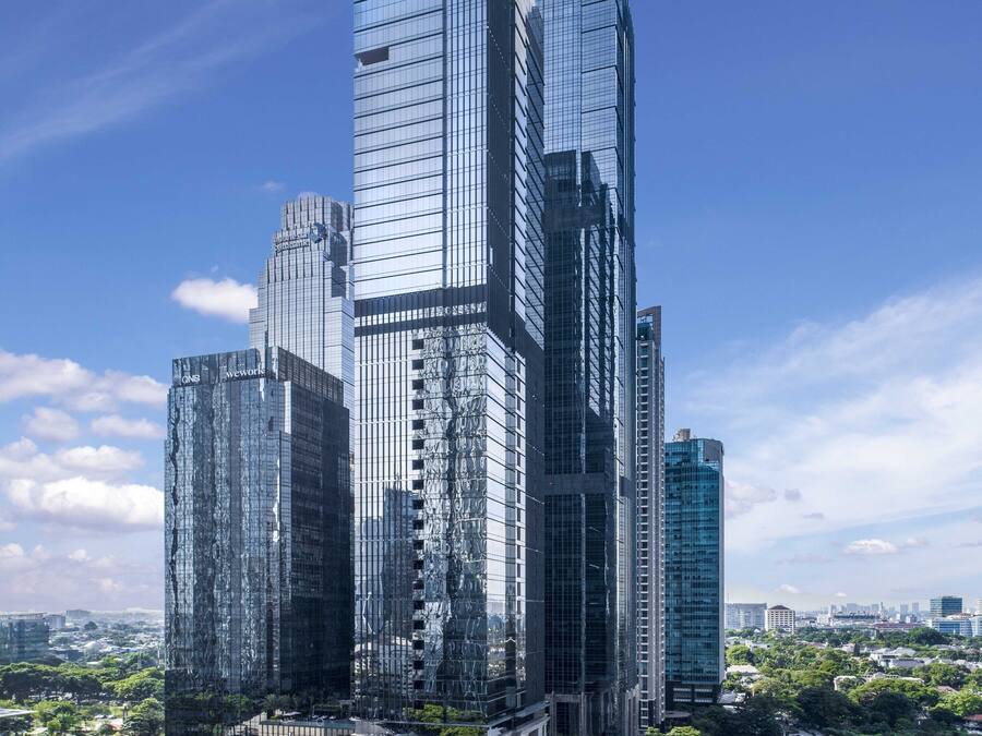 A modern skyscraper complex with multiple high-rise buildings, a central plaza with a fountain, and surrounding greenery.