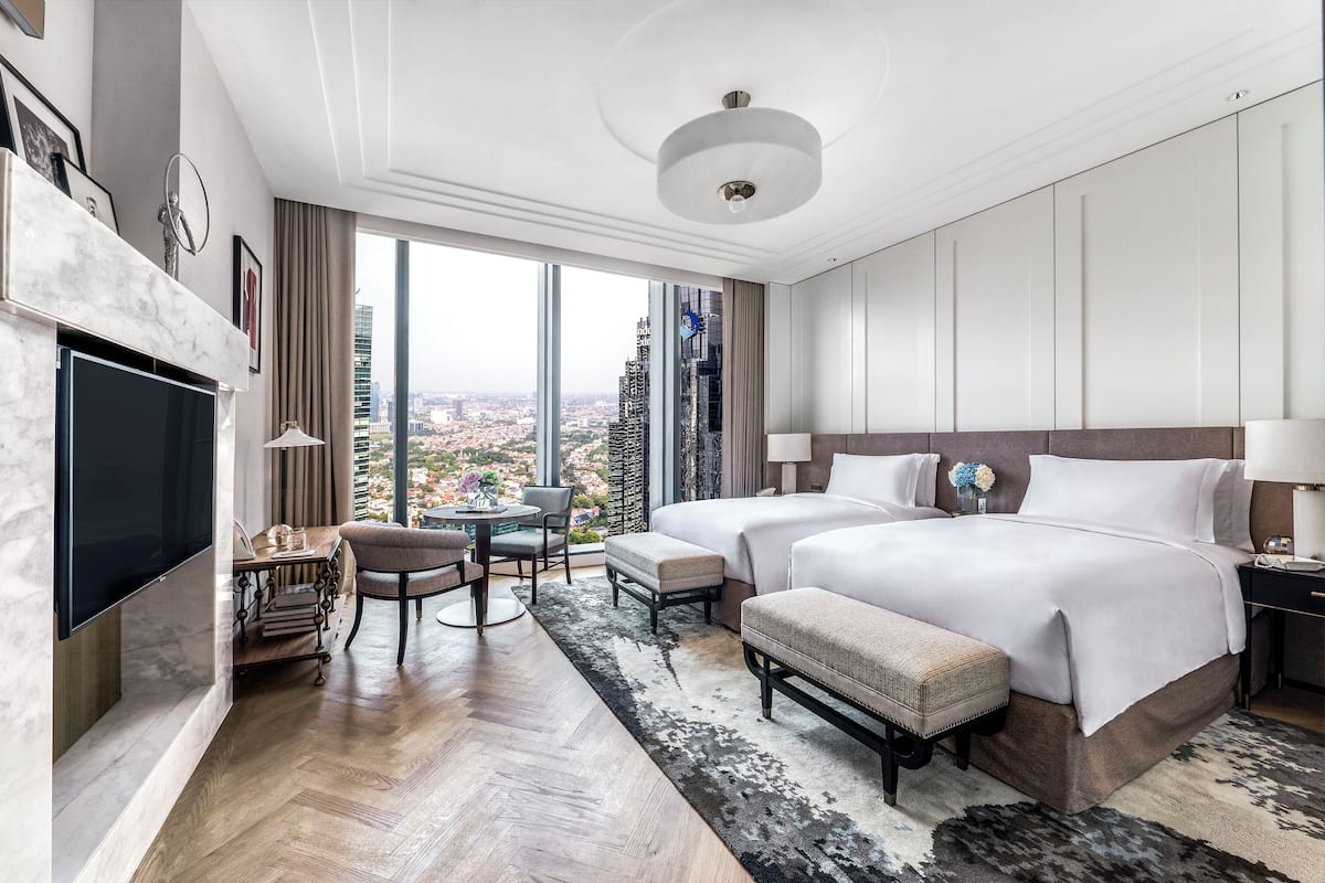 Quarto de hotel moderno com duas camas, uma televisão de tela plana, área de refeições e vista para a cidade.