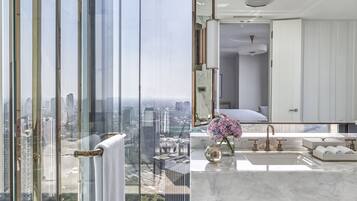 A modern bathroom with a large mirror, a sink, and a view of the city through floor-to-ceiling windows.