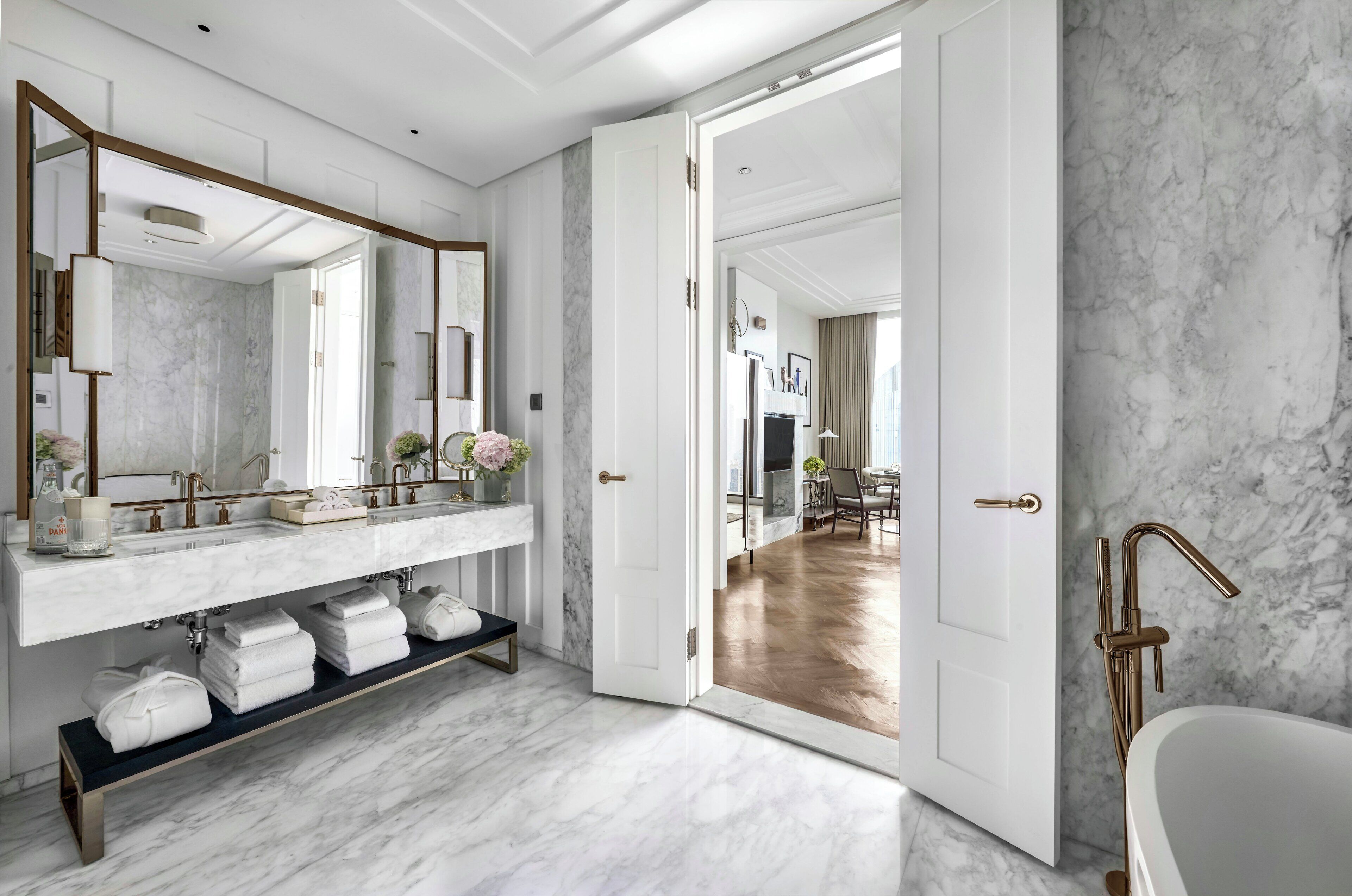 Un bagno moderno con un mobile bagno in marmo, una vasca e uno specchio grande.