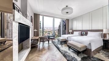 A modern hotel room with a large bed, a TV, a desk, and a view of the city.