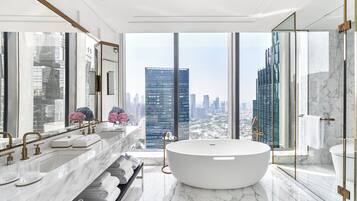 Un baño moderno con una bañera grande, un tocador doble y un amplio ventanal con vistas a la ciudad.