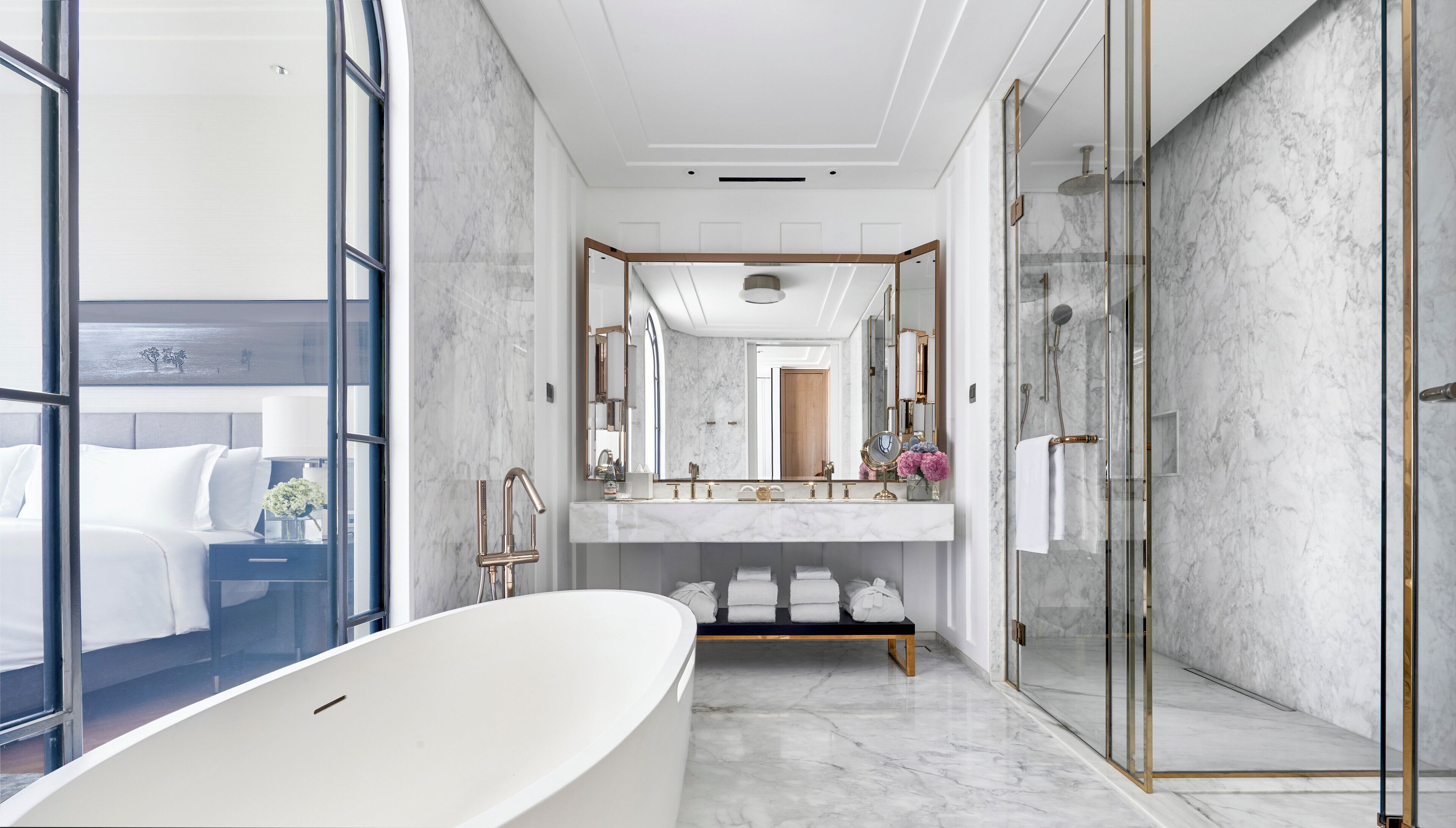 Un baño moderno con una bañera independiente, un espejo grande y una ducha con mampara de vidrio.