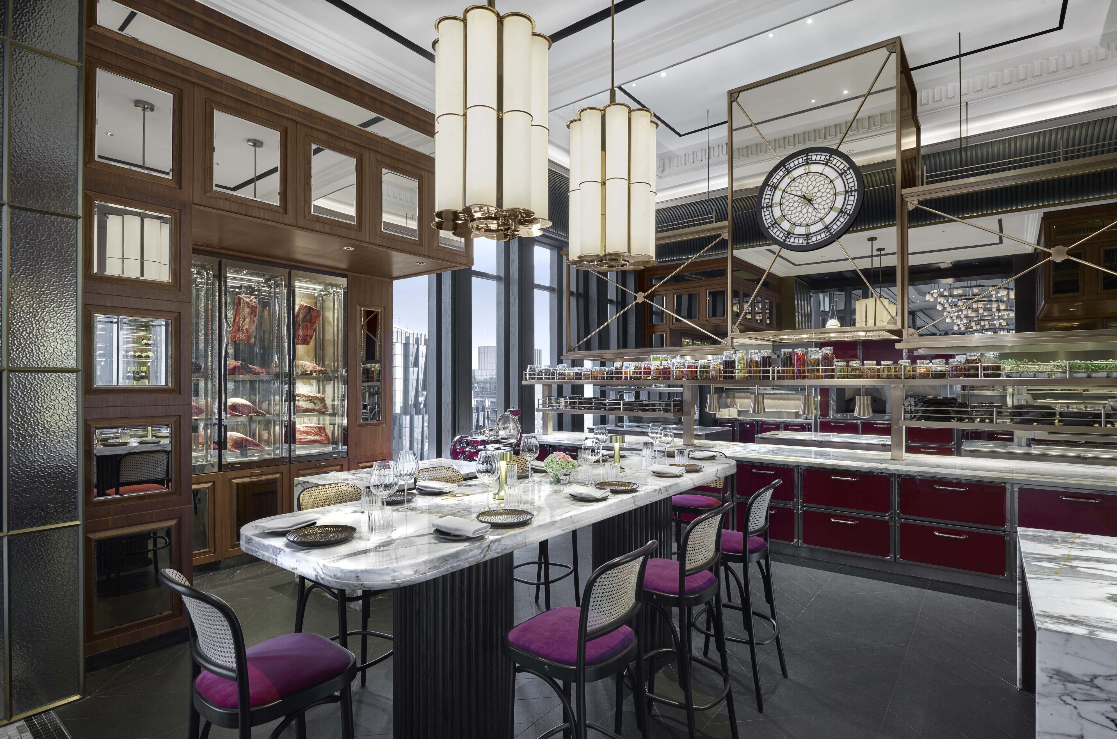 A modern restaurant with a marble bar, purple barstools, and a large clock on the wall.