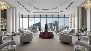 A spacious lobby with a central round table, comfortable seating, large windows offering city views, and elegant lighting fixtures. - The Langham, Jakarta (Jakarta)