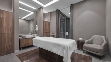 Relax in a serene space with a large bed, vanity, and armchair.