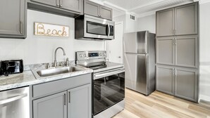 Een moderne keuken met grijze kastjes, roestvrijstalen apparatuur, een magnetron, oven en een koelkast.