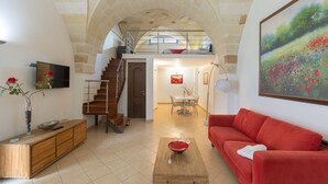 Ein geräumiger Wohnbereich mit Schlafgalerie, einem roten Sofa, einem Holztisch und einem Essbereich mit einer Kronleuchter.