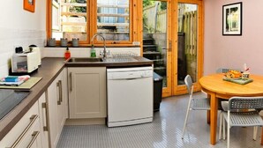 Cocina compacta con lavavajillas, un lavabo y ventana con vistas a un jardín.