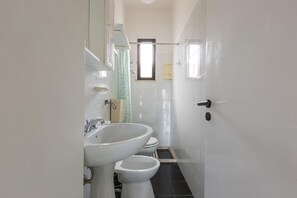 Ein Badezimmer mit Waschbecken, Toilette und einem Fenster.