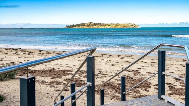 A beach with a staircase leading to a pier.