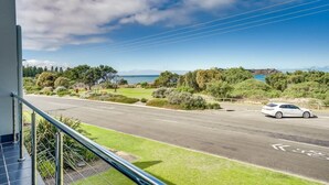 A road with a car, a clear sky, and a distant view of the sea.