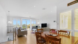 A spacious living area with a dining table, sofas, and a TV.