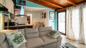 A cozy living room with a sofa, a coffee table, and a kitchen area in the background. - Apartment & Room Sunset Beach (Dubrovnik)