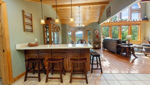 Une cuisine spacieuse dotée d’un grand îlot central, de tabourets de bar en bois et d’un coin repas avec un canapé et une table.