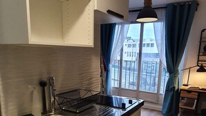 Una cocina compacta con un lavamanos de acero inoxidable, una pequeña encimera y una ventana con cortinas.