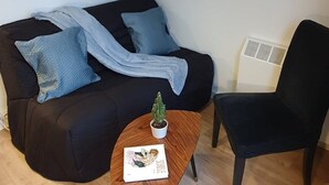 Una sala de estar moderna con un sofá negro, una mesa de centro de madera y un sillón negro. Una pequeña planta en maceta está sobre la mesa de centro.