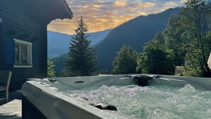 A hot tub with a mountain view, surrounded by trees and a cabin. - Chalet Pain Seigle (Riddes)