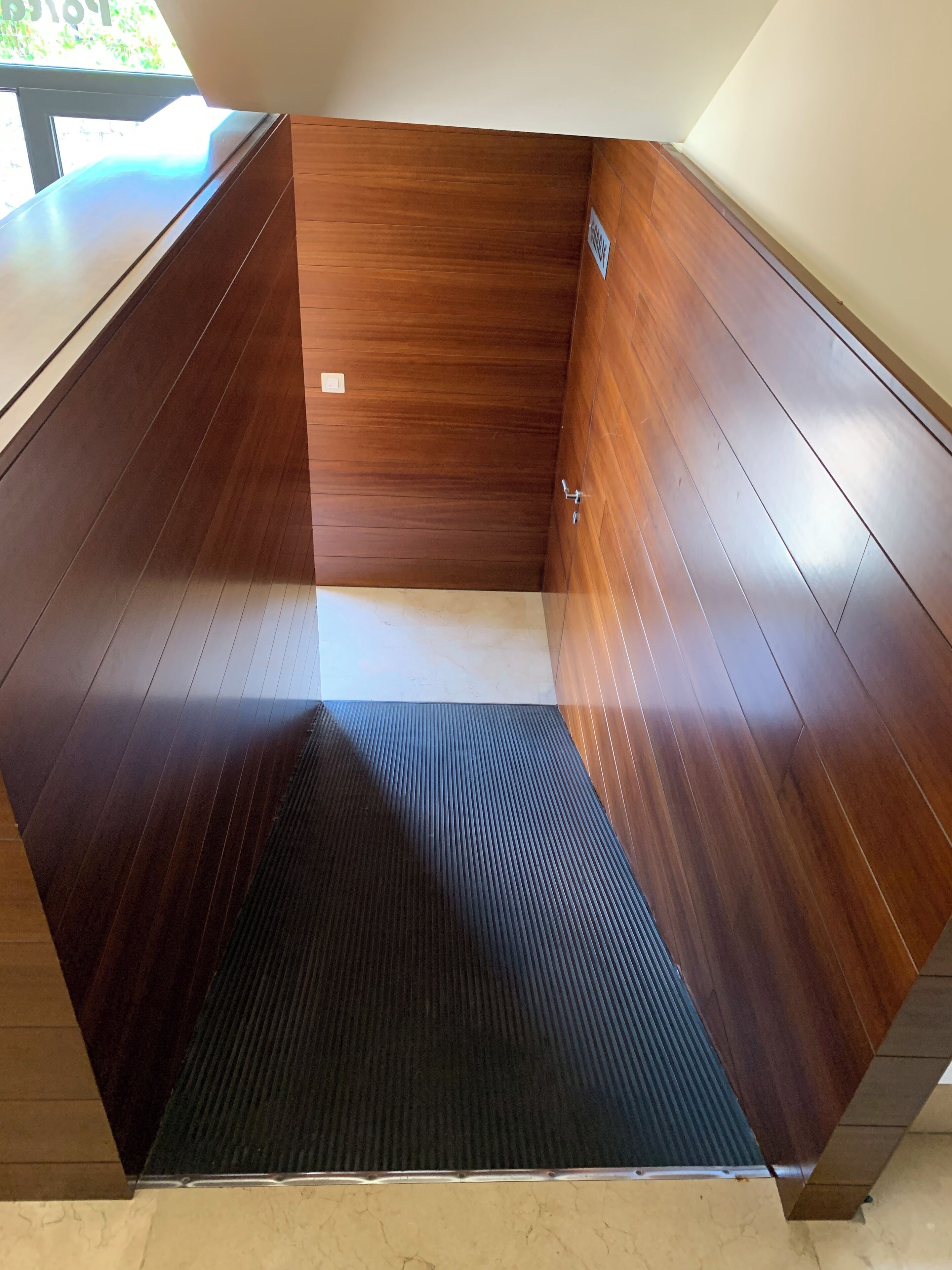 Een hoek van een kamer met houten lambrisering en een zwart, gestructureerd vloerkleed.