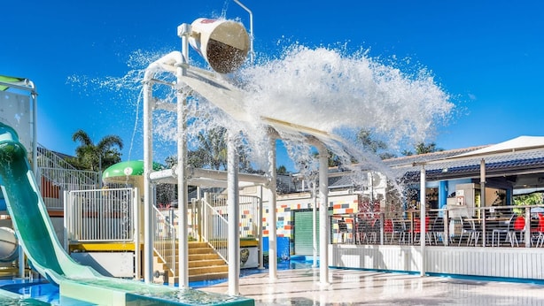 A water park with a water slide, a water fountain, and a pool. - 2-Bed Family Haven with Pools, BBQ & Playgrounds (Mermaid Beach)