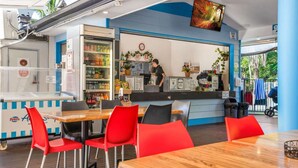 A restaurant with a counter, seating area, and a refrigerator stocked with beverages. - 2-Bed Family Haven with Pools, BBQ & Playgrounds (Mermaid Beach)