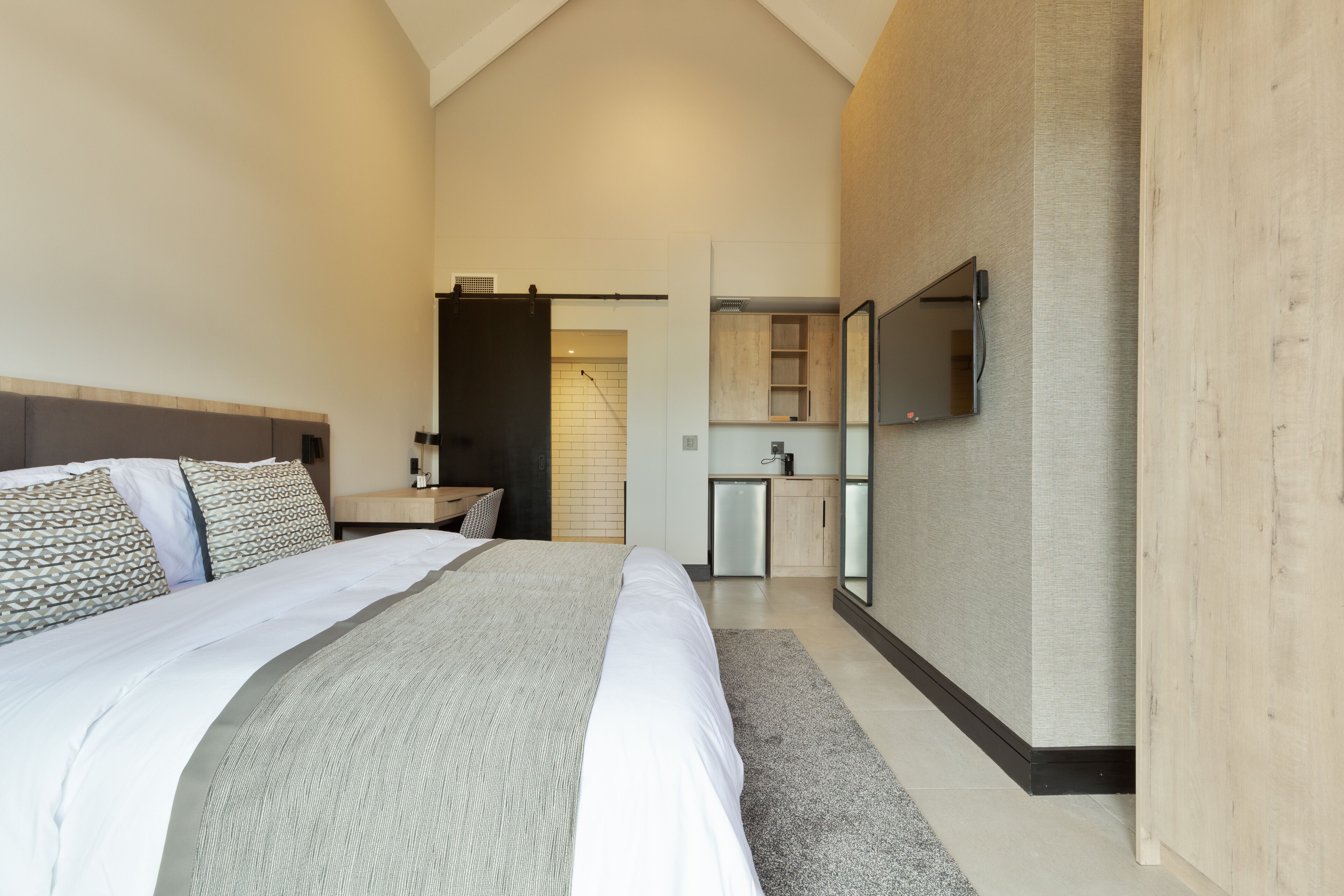 Une chambre moderne avec un grand lit, un bureau intégré et un miroir au mur.