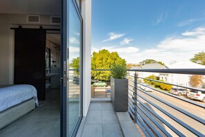 Een balkon met uitzicht op een straat en geparkeerde auto's.