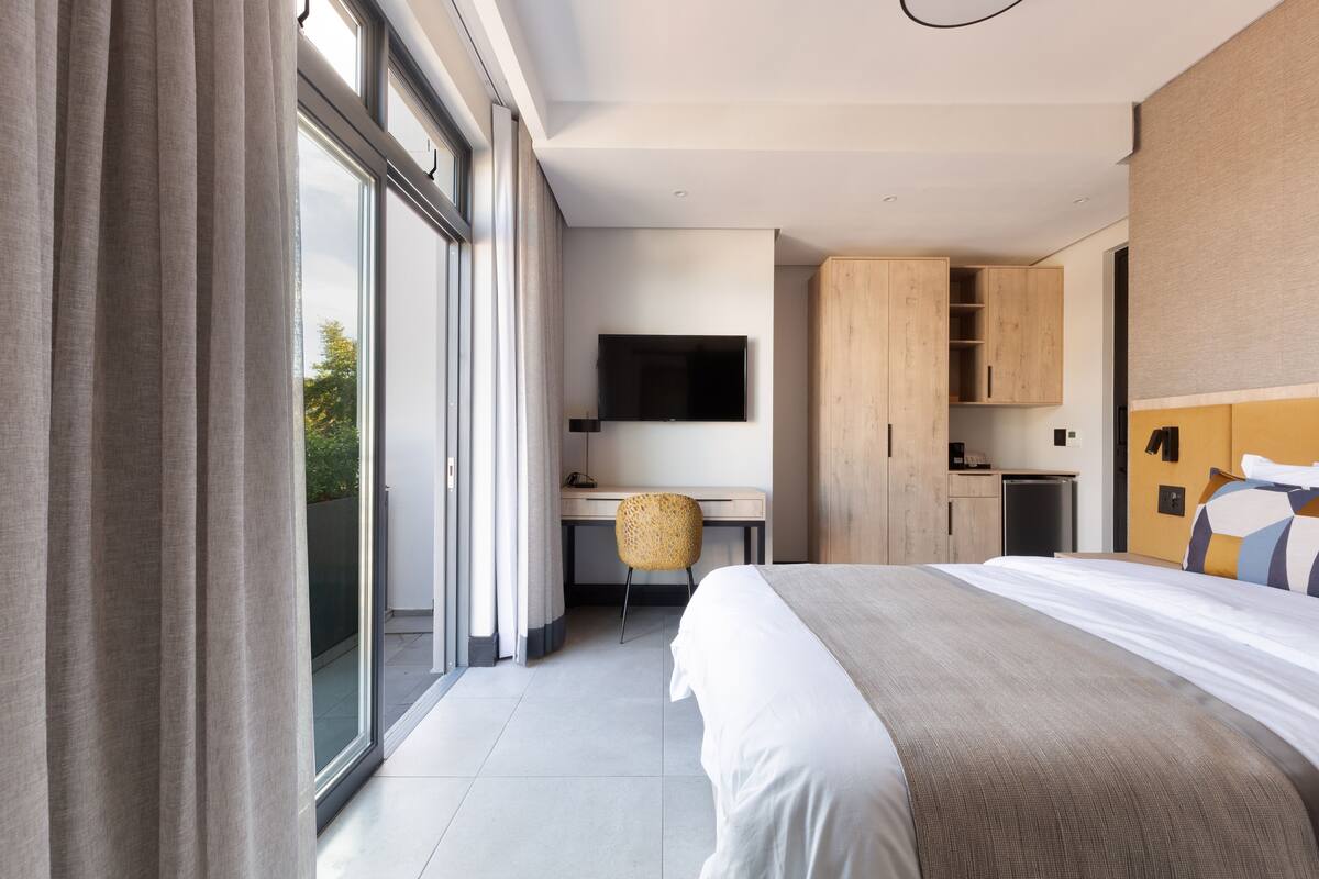 Una habitación de hotel moderna con una cama grande, un escritorio, una silla y un televisor.
