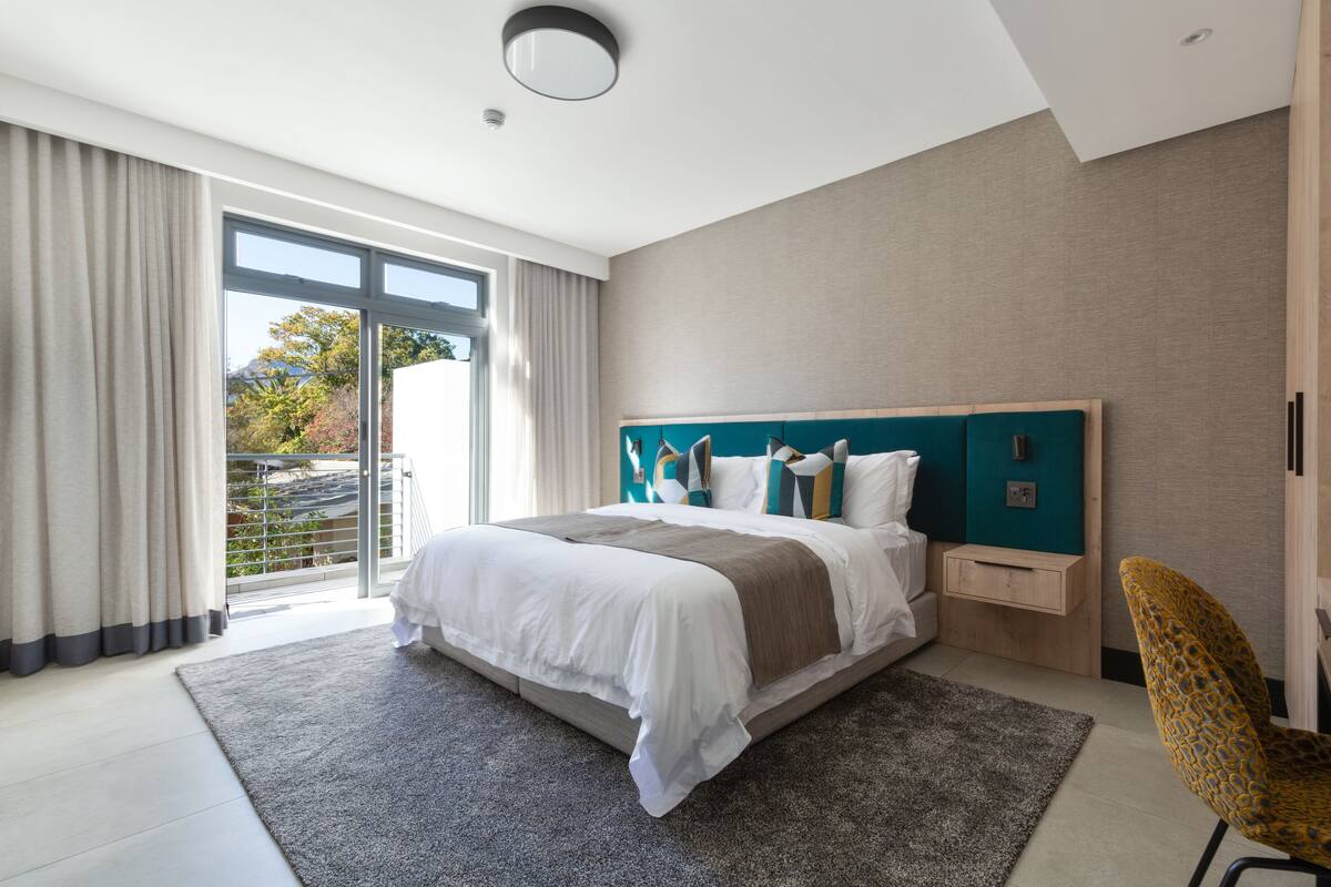 Una habitación de hotel moderna con una cama grande, vistas al exterior y un balcón.