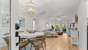 A spacious living area with a round dining table, wicker chairs, a sofa, and a chandelier. - 3 BD/2 BA  Pet Friendly Summerwind! Amenity Access included! Close to Beaches, Pools, Dining & Golf! (Seabrook Island)