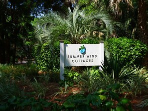 A sign for Summer Wind Cottages surrounded by lush greenery.