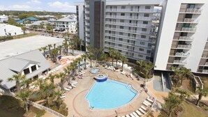 Un hotel con piscina, varios balcones y zonas ajardinadas a su alrededor.