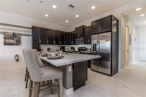 Enjoy cooking in this kitchen with sleek cabinetry, stainless steel appliances, and a spacious island with seating.