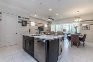 Enjoy meals in the well-lit kitchen with a central island and dishwasher, adjacent to a dining area with a table and chairs.