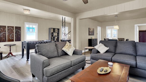 Ein geräumiges Wohnzimmer mit grauen Sofas, einem Couchtisch und einem Kicker.