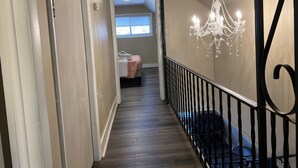 Ein Flur mit einem Chandelier, einem Bett und einer Treppe.