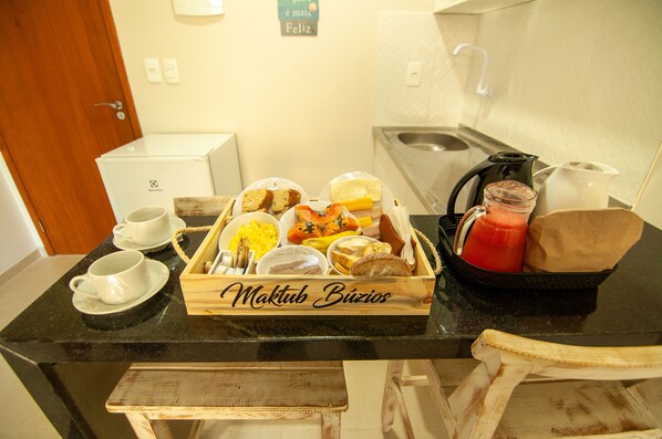 A breakfast buffet with various food items and beverages on a black countertop. - Pousada Maktub (Búzios)