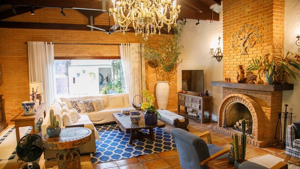 A cozy living room with a fireplace, a sofa, a coffee table, and a chandelier.