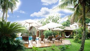 A tropical outdoor area with a pool, lounge chairs, and umbrellas.