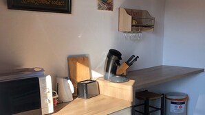 A kitchen with a microwave, toaster, coffee maker, and a trash can.