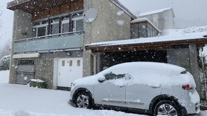 A two-story house with a garage and a car covered in snow.