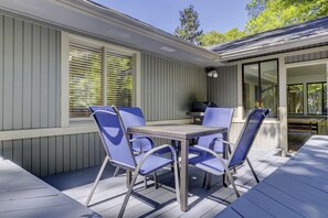 Portico coperto con tavolo e quattro sedie, un barbecue e vista sulla casa.