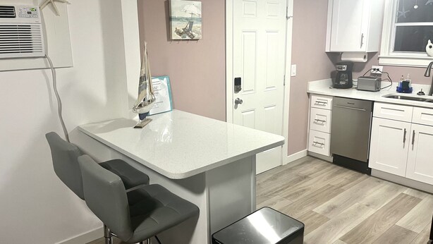 A modern kitchen with white cabinets, a built-in dishwasher, and a coffee maker. - Beachy Paradise (Indian Rocks Beach)