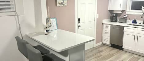 A modern kitchen with white cabinets, a built-in dishwasher, and a coffee maker.