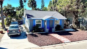 A small, single-story house with a blue and white exterior, a driveway, and a car parked in front. - Beachy Paradise (Indian Rocks Beach)