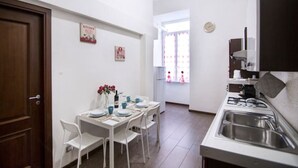 A compact kitchen with a dining area, a sink, and a window with curtains. - Roman 2BR Apartment @ 2min near Vatican Museums & 8 min Basilica St.Peter's (Roma)
