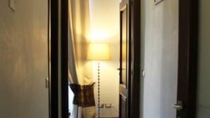 A narrow hallway with a lamp and a door leading to a room with a bed and curtains. - Roman 2BR Apartment @ 2min near Vatican Museums & 8 min Basilica St.Peter's (Roma)