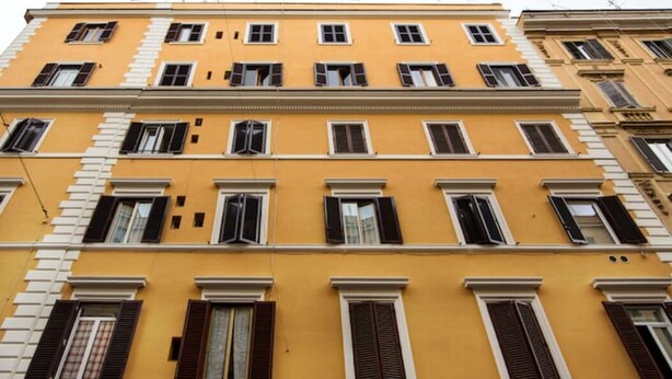 A multi-story building with a yellow facade, multiple windows with shutters, and a consistent architectural style. - Roman 2BR Apartment @ 2min near Vatican Museums & 8 min Basilica St.Peter's (Roma)