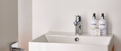 A bathroom with a white sink, a wooden cabinet below, and a mirror with a wooden frame.