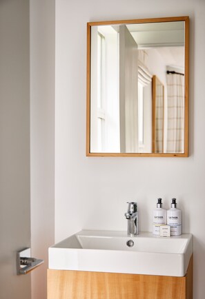 A bathroom with a white sink, a wooden cabinet below, and a mirror with a wooden frame.